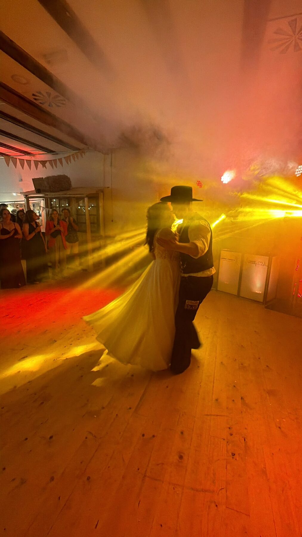 Brautpaar im Country-Look beim Hochzeitstanz mit rot-orangefarbener Beleuchtung