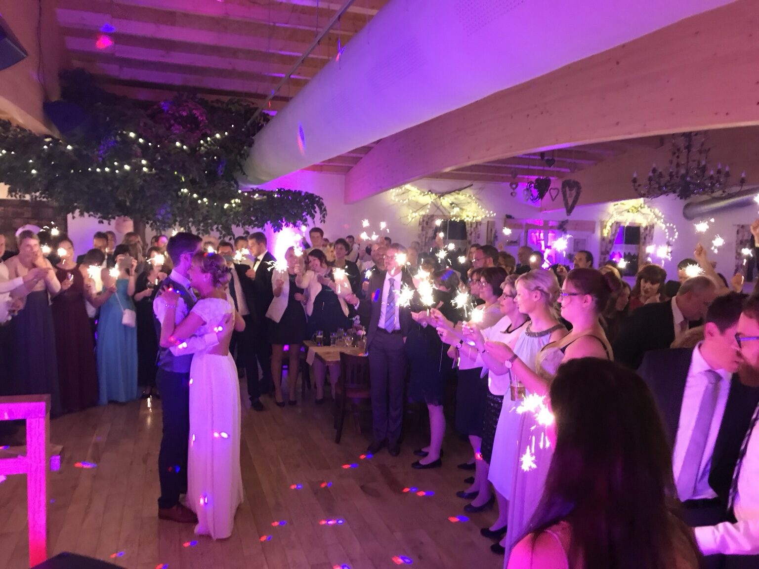 Brautpaar beim Hochzeitstanz, umgeben von seinen Gästen mit Wunderkerzen