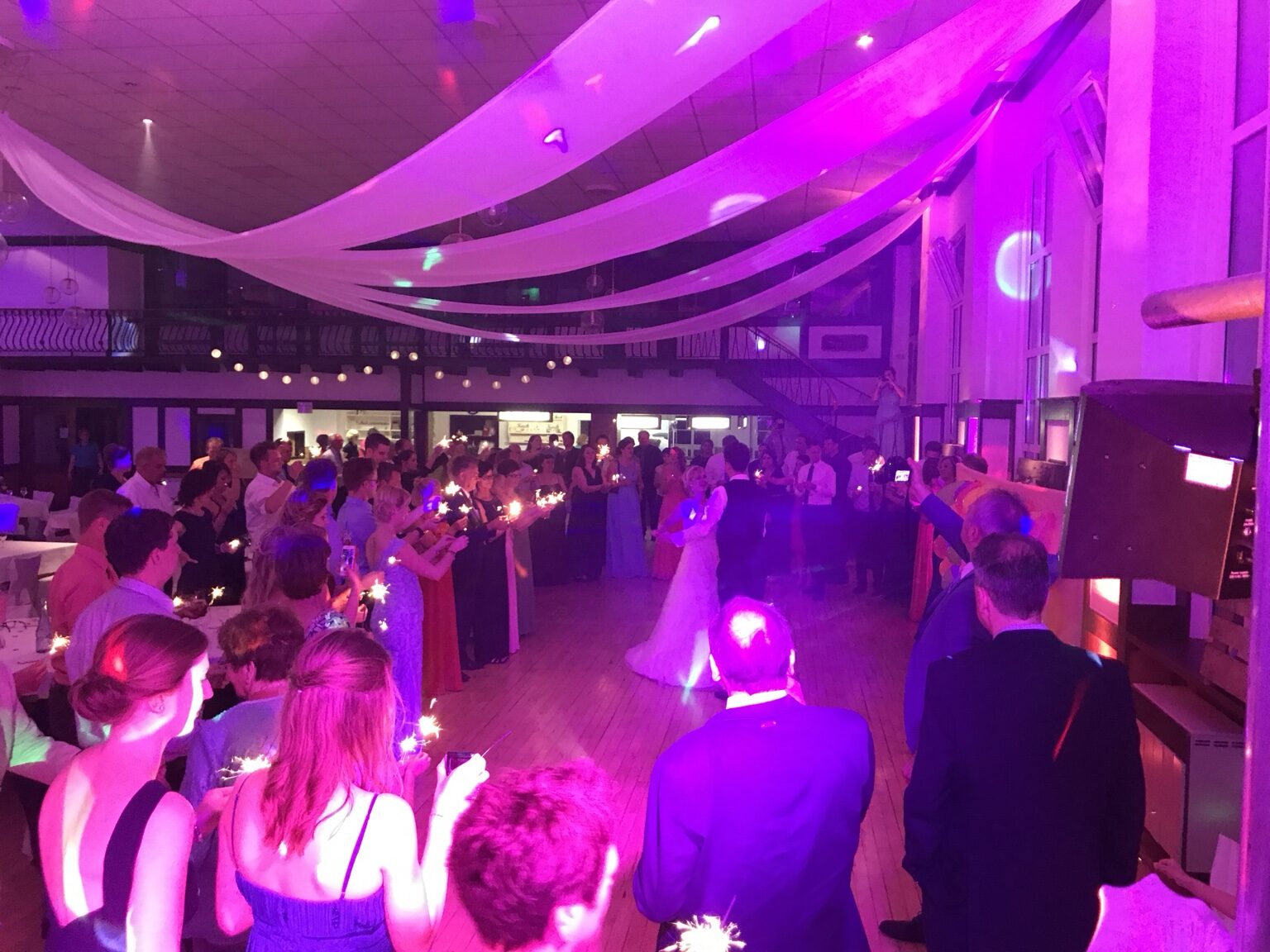 Hochzeitstanz umgeben von Gästen und stimmungsvoller Beleuchtung