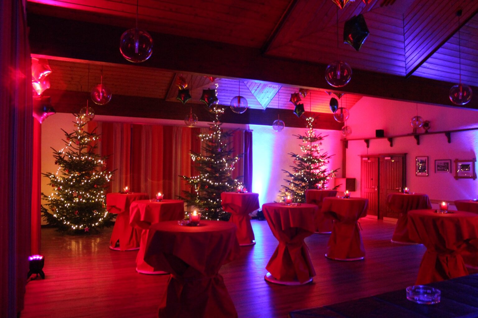 Festlich beleuchtete Lounge mit Stehtischen und Weihnachtsbäumen
